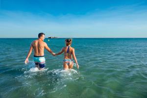 a man and a woman walking in the water at Hotel & Spa Gil de France Cap d'Agde in Cap d'Agde