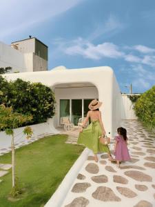 a woman and a little girl walking in front of a house at Kenting South Border DeSign Hotel in Eluan