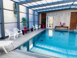 una piscina con sillas, una mesa y un edificio en Hotel & Spa Gil de France Cap d'Agde, en Cap d'Agde