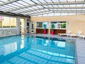 a large swimming pool with two chairs and a building at Hotel & Spa Gil de France Cap d'Agde in Cap d'Agde
