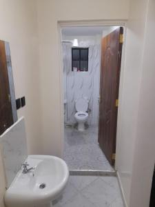 La salle de bains est pourvue de toilettes blanches et d'un lavabo. dans l'établissement The seed, à Nairobi
