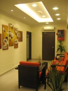 een lobby met een wachtkamer met oranje stoelen en een tafel bij GM Holiday Hotel in Lumut