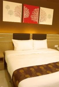 a bed in a room with paintings on the wall at GM Holiday Hotel in Lumut