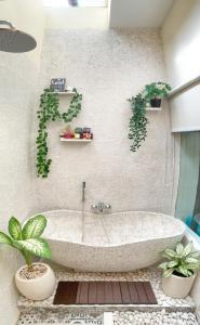 eine Badewanne im Bad mit Pflanzen an der Wand in der Unterkunft UNIQUE HOUSE UMA DESA in Kesiman