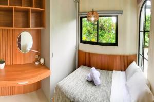 a bedroom with a bed with a desk and a window at UNIQUE HOUSE UMA DESA in Kesiman