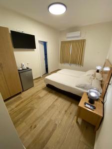 a small room with a bed and a television at Berger Hotel in Tiberias
