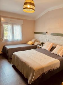 a bedroom with two beds and a large window at Hôtel le Nid in Argelès-sur-Mer