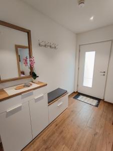 a bathroom with white cabinets and a mirror and a door at Ferienwohnung Landliebe in Ravensburg