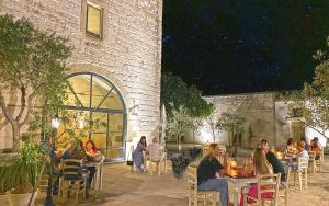 a group of people sitting at tables outside of a building at Masseria La Millenaria in San Foca