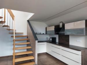 a staircase in a kitchen with white cabinets and a stair case at Ferienwohnung Goldeckblick in Seeboden