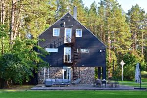 une maison avec un toit en gambrel et une terrasse dans l'établissement Villa Rata, à Ratnyčia