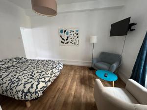 a bedroom with a bed and a couch and a chair at Appartement Cosy Charme Ancien in Thizy-les-Bourgs +2 photos