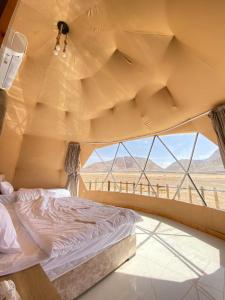 a bed in a tent with a view of the desert at Wadi rum sky luxury in Disah
