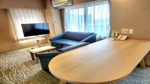 a room with a table and a couch and a tv at Hotel Alpha Inn Akita in Akita