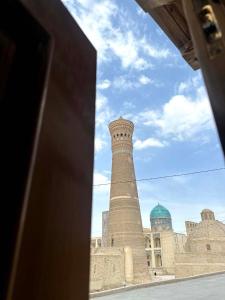 un bâtiment avec une tour d'horloge devant lui dans l'établissement Suzani National House, à Boukhara
