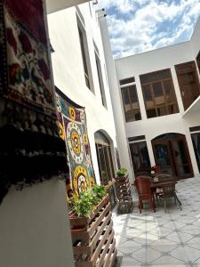 - un bâtiment avec une terrasse dotée d'une table et d'un tapis dans l'établissement Suzani National House, à Boukhara
