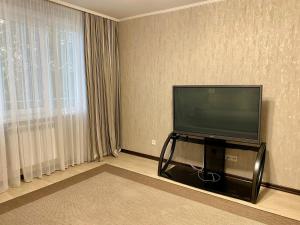 uma sala de estar com uma televisão de ecrã plano e uma janela em UKA Comfort, 3х комнатная в центре. em Öskemen