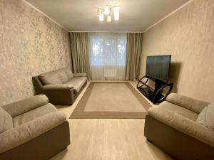 uma sala de estar com 2 sofás e uma televisão de ecrã plano em UKA Comfort, 3х комнатная в центре. em Öskemen