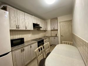 uma cozinha com armários brancos e uma mesa e cadeiras em UKA Comfort, 3х комнатная в центре. em Öskemen