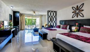 1 dormitorio con 2 camas y sala de estar en Suites Corazon, en Playa del Carmen