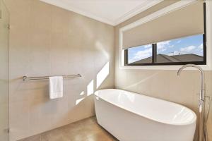bagno bianco con vasca e finestra di Pet-Friendly Paradise Retreat with Pizza Oven a Eglinton Altre 49 foto