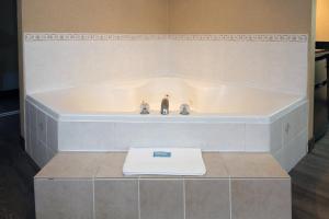 een bad met 2 kranen en een handdoek bij Holiday Inn Express Hotel & Suites Vernon, an IHG Hotel in Vernon