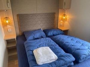 - un lit avec une couette bleue et un oreiller dans l'établissement Traumblick, Traumlage Nr 31 erste Reihe direkt am Wattenmeer, à Westerland