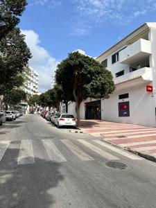 una strada vuota con auto parcheggiate sul lato di un edificio di Alojamiento Joan Miro a Torremolinos
