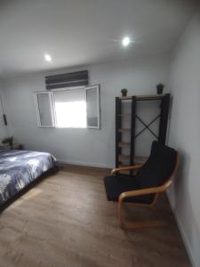 a bedroom with a bed and a chair and a window at Corazón urbano in Málaga
