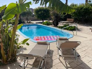 una piscina con 2 sillas, una mesa y una piscina en Villa Chrysa Rhodes, en Afantou