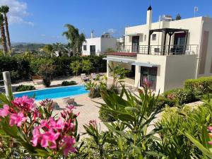 a large white house with a swimming pool and flowers at Villa Chrysa Rhodes in Afantou