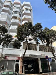 Un alto edificio bianco con un albero davanti di Alojamiento Joan Miro a Torremolinos Altre 7 foto