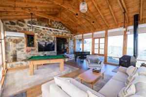 un soggiorno con tavolo da biliardo e parete in pietra di Serenity Mountain ad Askas