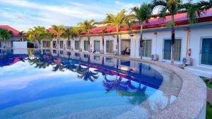 a swimming pool in front of a building with palm trees at Green Mango Resort in Danao