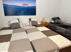 a bedroom with two beds and a painting on the wall at La Graciosita Traditional Home in Caleta de Sebo