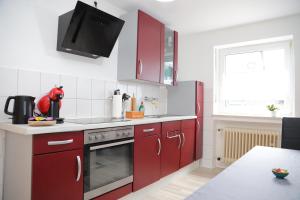 a kitchen with red cabinets and a stove top oven at Zentrale, ruhige Wohnung in Innenstadt - Küche, Parkplatz, Terrasse, SmartTV, Netflix in Bitburg