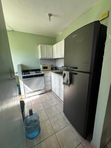 una cucina con frigorifero nero e armadietti bianchi di casa nagüera a Nagua