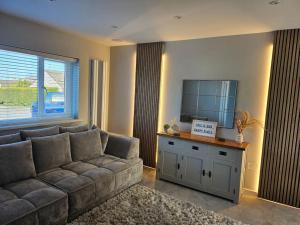 a living room with a couch and a flat screen tv at The Tranquil Retreat in Llanfechell