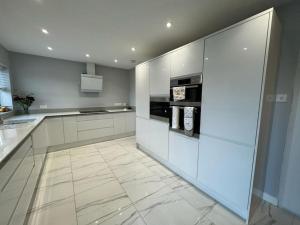 a large kitchen with white cabinets and appliances at The Tranquil Retreat in Llanfechell