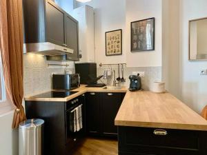 uma cozinha com armários pretos e uma bancada em L'Ambre - Appartement Raffiné em Perpignan