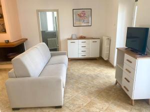 ein Wohnzimmer mit einem weißen Sofa und einem TV in der Unterkunft Maddalena Lake Como view terraces in Lezzeno