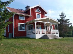 Casa roja con porche blanco y escaleras en Swedish Paradise Garden & Lake Retreat 