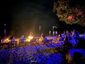 a group of people sitting around a fire on a beach at night at Phi Phi Relax Beach Resort in Phi Phi Islands
