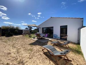 a patio with chairs and an umbrella and a house at HOOliRé17 3étoiles in Ars-en-Ré