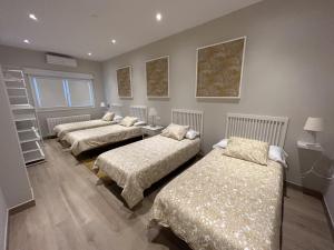 a room with three beds in a room at La Casa del Tejado Verde Toledo in Toledo
