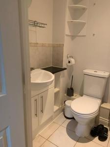 een witte badkamer met een toilet en een wastafel bij 3 Bedroom Home Near Windsor Castle, Legoland, & Heathrow in Slough