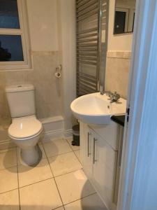 La salle de bains est pourvue de toilettes et d'un lavabo. dans l'établissement 3 Bedroom Home Near Windsor Castle, Legoland, & Heathrow, à Slough
