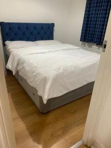 a bed with a blue headboard in a bedroom at 3 Bedroom Home Near Windsor Castle, Legoland, & Heathrow in Slough
