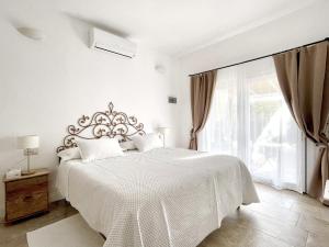 a white bedroom with a large bed and a window at Sea Love in Olbia