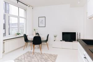 a white living room with a table and chairs at City Center Maakri Apartment in Tallinn